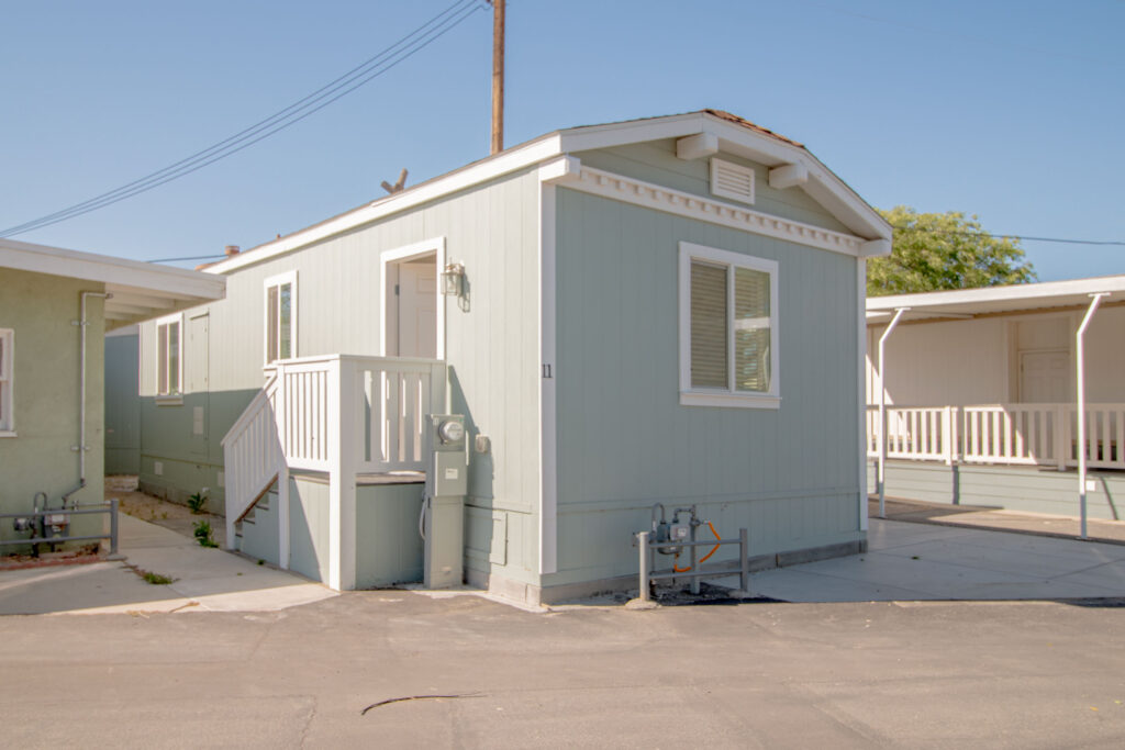 Front view left side of a modern mobile home for sale with a well-maintained exterior, situated in a serene residential area.