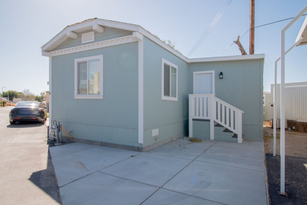 Front view right side of a modern mobile home for sale with a well-maintained exterior, situated in a serene residential area.