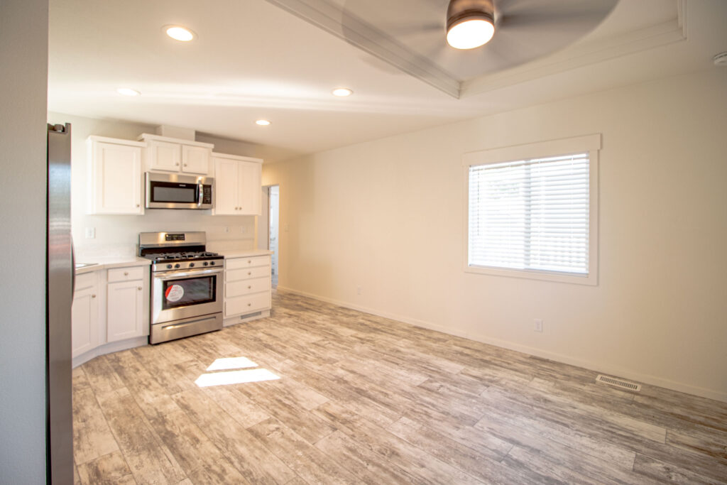 Interior view of a mobile home for sale modern kitchen with stainless steel appliances, white cabinetry, and a central island in a manufactured home.